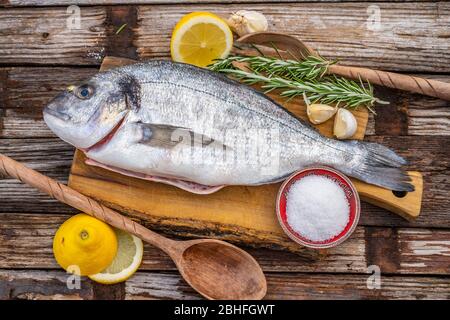 poisson frais cru de basse mer sur le concept de cuisine de planche à découper en bois sur un fond sombre en bois vue sur le dessus Banque D'Images