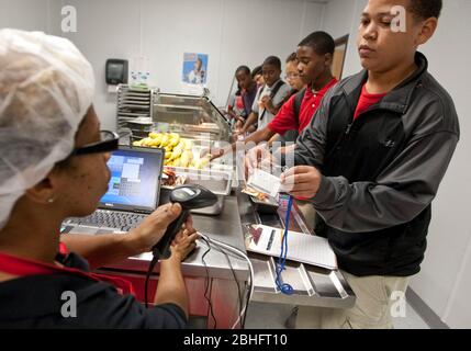 Houston, Texas juin 2012: Un employé de cafétéria utilise un lecteur portatif pour lire des informations de code-barres sur les cartes de repas des élèves dans une école secondaire de charte publique. ©Marjorie Kamys Cotera/Daemmrich Photographie Banque D'Images