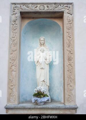 Capitale votive avec statue blanche de la Vierge marie et de bébé jésus dans ses bras. Banque D'Images