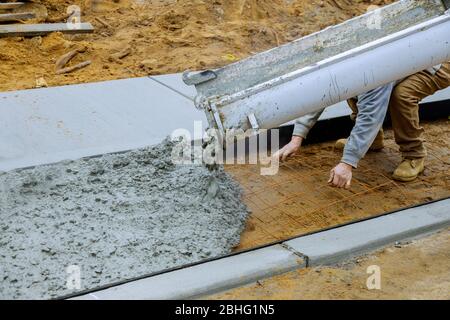 Mélangeur en béton pour les travailleurs avec ciment versant sur le trottoir résidentiel Banque D'Images