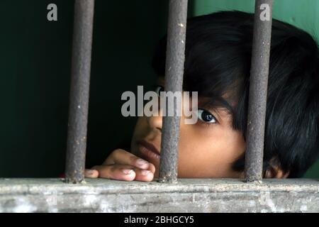 Portrait d'un enfant triste et innocent regardant la fenêtre. Une fille triste regarde attentivement à travers la fenêtre à la maison. Petite fille forcée de rester à la maison Banque D'Images