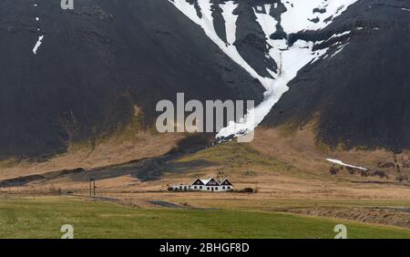 Paysage islandais typique avec fermes sous la montagne couverte de neige en Islande. Centre-sud-est de l'Islande Banque D'Images