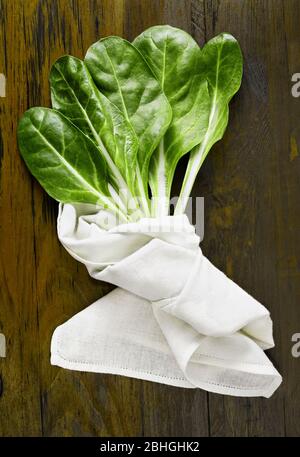 Feuilles de verger -verger suisse - sur table en bois , plusieurs feuilles vertes avec des tiges blanches recouvertes de tissu de coton blanc Banque D'Images