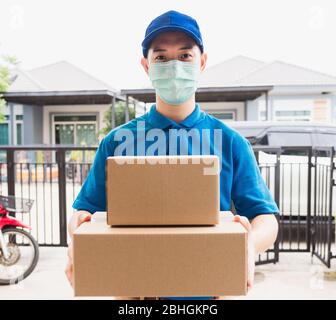 Livraison asiatique express courier jeune homme utiliser des boîtes de livraison à la femme client il porte un masque de protection au front de la maison, sous le couvre-feu de la table de quarantaine Banque D'Images