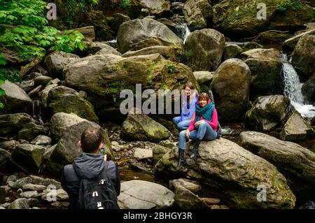 Les touristes féminins posant pour la photo sur les rochers à la chute d'eau de Torc dans le parc national de Killarney, comté de Kerry, Irlande Banque D'Images