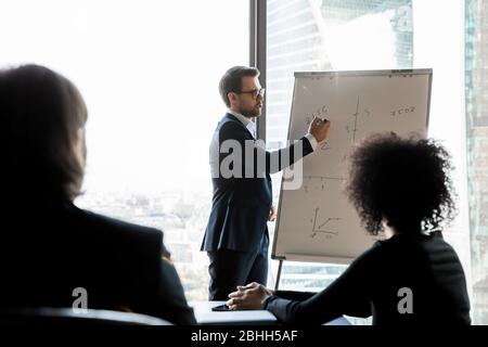 Un homme d'affaires confiant guide le personnel de formation lors de la réunion d'information, à l'aide d'un tableau de conférence Banque D'Images