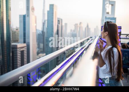 Jeune femme tout en profitant de la vue sur les gratte-ciel et le coucher du soleil Banque D'Images