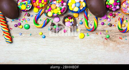 Bonbons colorés, œufs au chocolat et sucettes sur fond en bois. Vue de dessus avec espace de copie. Banque D'Images