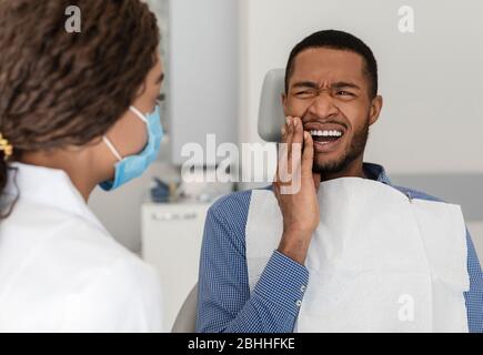 Homme noir dans une chaise dentaire souffrant de douleur dentaire Banque D'Images