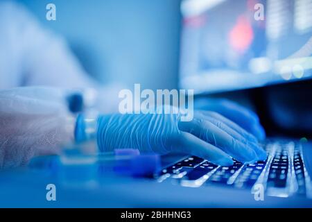 Les scientifiques en recherche médicale travaillent en ligne test sanguin informatique sur lame en laboratoire moderne. Couleur bleue, épidémie de virus Banque D'Images