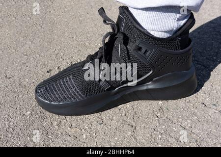 chaussures de course à pied sombres sur l'asphalte au soleil . Banque D'Images