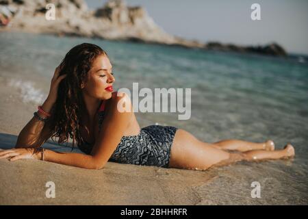 Jolie jeune femme vêtue de bikini relaxant sur le bord de mer en vacances d'été Banque D'Images