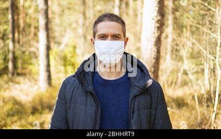 Homme en masque médical au milieu de la forêt. Banque D'Images