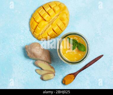 smoothie mangue, gingembre, curcuma dans un bocal en verre sur fond bleu. vue du dessus Banque D'Images