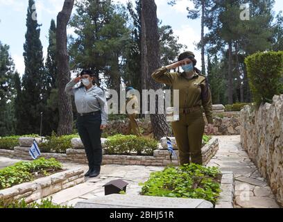 Jérusalem, Israël. 26 avril 2020. Les soldats israéliens portent un masque de protection contre le coronavirus, tout en saluant les tombes des soldats tombés, avant le jour commémoratif, dans le Mont. Cimetière militaire Herzl, le dimanche 26 avril, à Jérusalem. Les familles endeuillées ne pourront pas visiter le cimetière le jour commémoratif d'Israël pour les soldats tombés et les victimes de terreur, qui commence au coucher du soleil, le 27 avril, dans un effort pour arrêter la propagation de la COVID-19. Photo de Debbie Hill/UPI crédit: UPI/Alay Live News Banque D'Images