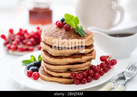 Pile de crêpes de blé entier avec baies sur table blanche. Délicieux petit déjeuner sucré Banque D'Images