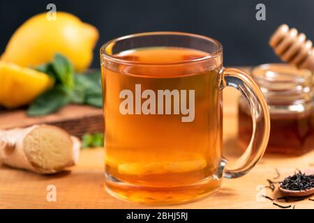 Thé au citron au gingembre dans une tasse de verre sur une table en bois, vue rapprochée. Thé au gingembre chaud Banque D'Images