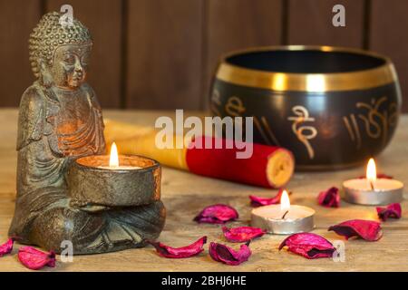 Bouddha assis en pierre, bougies et bol tibétain. Autour de la bougie, l'atmosphère de méditation. Confort et détente à la maison Banque D'Images