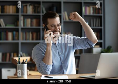 Homme d'affaires souriant et satisfait qui fait un appel téléphonique, entend de bonnes nouvelles Banque D'Images