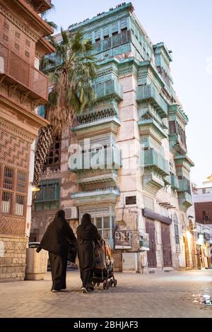 Djeddah / Arabie Saoudite - 16 janvier 2020: Deux femmes musulmanes portant l'abaya et portant la poussette dans le centre historique Al-Balad avec un bâtiment coloré en arrière-plan Banque D'Images