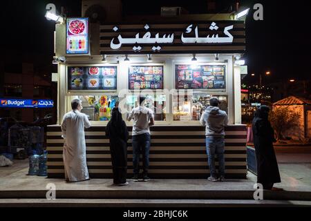 Djeddah / Arabie Saoudite - 16 janvier 2020: Couple musulman attendant devant le stand de nourriture sur la promenade du parc devant la fontaine du roi Fahd Banque D'Images