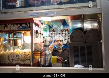 Djeddah / Arabie Saoudite - 16 janvier 2020: Portrait du travailleur à côté de la machine à popcorn dans l'étalage alimentaire sur la promenade du parc en face de la fontaine du roi Fahd Banque D'Images