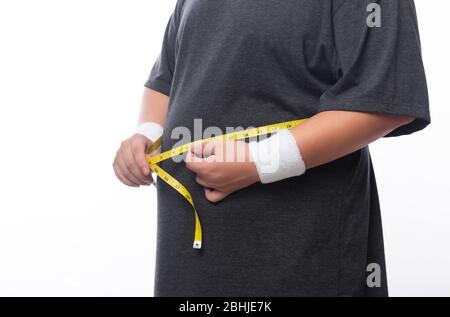 Homme de graisse tenant un ruban de mesure pour vérifier son corps isolé sur fond blanc. Banque D'Images