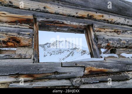 Ancienne cabine avec montagnes en arrière-plan dans un cadre d'hiver Banque D'Images