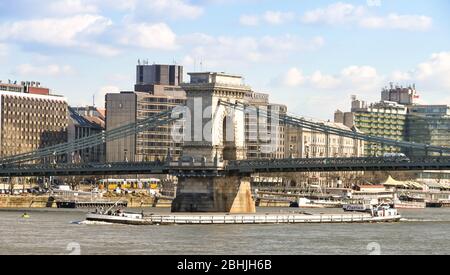 BUDAPEST, HONGRIE - MARS 2018 : une longue barge industrielle passant sous le pont de la chaîne qui traverse le Danube dans le centre-ville de Budapest Banque D'Images