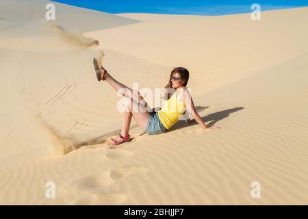 Femme assise sur le sable dans le désert, portant un tee-shirt et un short Banque D'Images