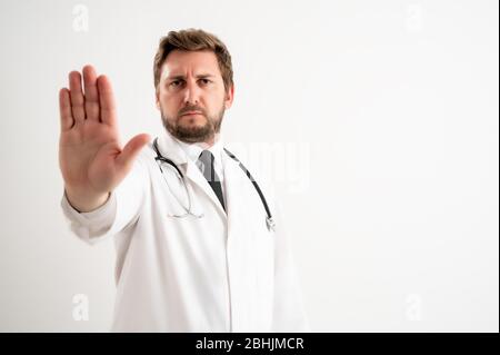 Portrait d'un médecin mâle avec stéthoscope en uniforme médical montrant un signe d'arrêt se posant sur un fond blanc isolé Banque D'Images