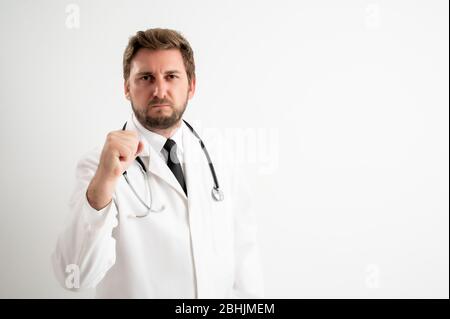 Portrait d'un médecin mâle avec stéthoscope en uniforme médical montrant un poing se posant sur un fond blanc isolé Banque D'Images