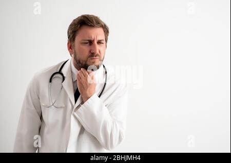 Portrait d'un médecin mâle avec stéthoscope en uniforme médical avec bras ouverts regardant vers le haut, mal de gorge posant sur un fond blanc isolé Banque D'Images