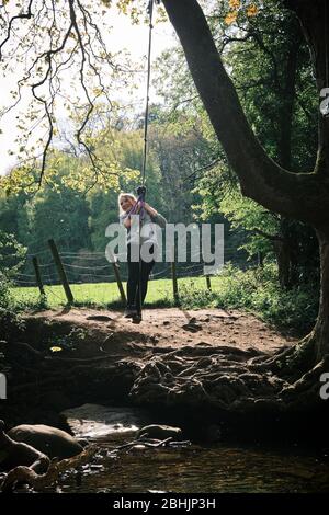 Une fille rit alors qu'elle balance sur une corde dans les bois à Shipley Glen, Saltaire, West Yorkshire. ROYAUME-UNI Banque D'Images