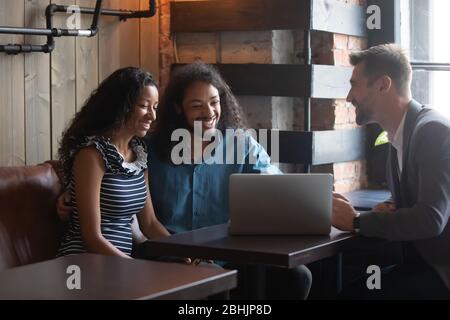 Couple multiracial souriant coopérant avec un consultant masculin dans un café Banque D'Images