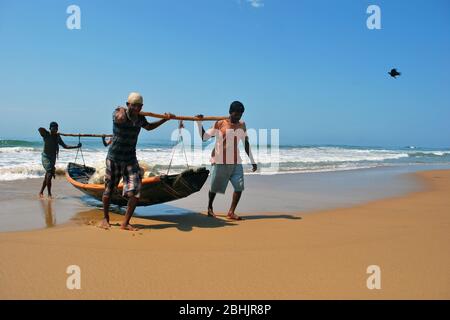 Les pêcheurs qui mettent leur bateau de pêche à la plage de Puri. Banque D'Images