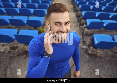 Portrait d'un jeune athlète masculin heureux dans un casque et une horloge dans un stade dans le brouillard. Banque D'Images