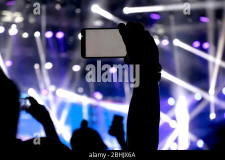 La collecte de mémoire numérique perd de capacité d'être présent, silhouette d'un homme part la prise de concert avec son smart phone Banque D'Images