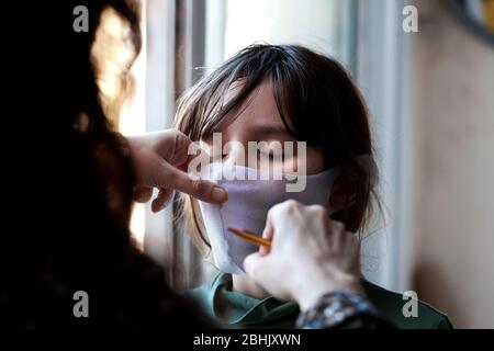 Une femme espagnole tailleur un masque pour son fils de 11 ans. Banque D'Images