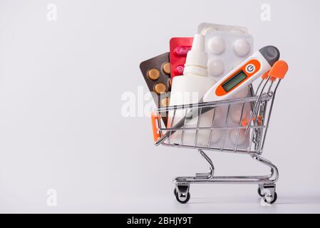 Concept de vitamines de prévention. Gros plan photo du panier plein de pilules et thermomètre numérique isolé sur fond gris avec blanc vide spac Banque D'Images