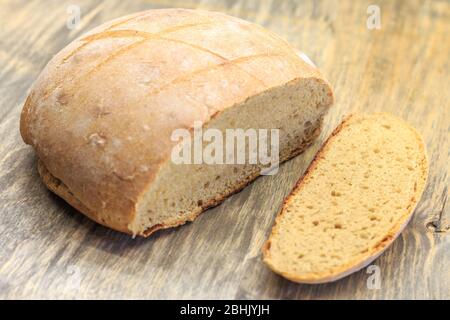 juste cuit et couper un pain rond de pain fait avec de la farine de blé entier et du levain sur une surface en bois Banque D'Images