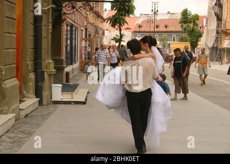 Sibiu, Roumanie. Ancienne coutume de 'sarler' la mariée pendant le mariage en échange d'une compensation. Homme transportant une mariée dans les rues. Banque D'Images