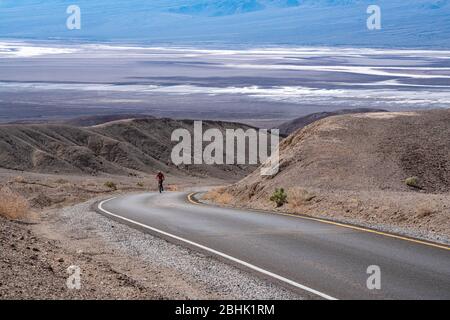 Un cycliste solitaire persévère sur la montée le long de la promenade Artist's Palette dans le parc national de la Vallée de la mort Banque D'Images