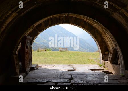 Vue à travers une arche du complexe du monastère de Haghpat en Arménie montrant l'herbe et la montagne. Aussi connu sous le nom de Haghpatavank. Arc construit dans un monolithe. Banque D'Images