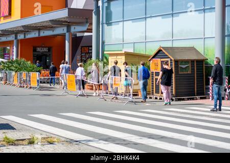 Distanciation sociale des personnes en attente en file d'attente devant le magasin de marché de la construction pendant le coronavirus covid-19. Bande sur le sol Banque D'Images