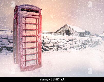 Un téléphone rouge traditionnel recouvert de neige, Dartmoor, Devon, Royaume-Uni, Banque D'Images