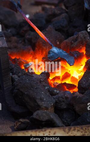 Four de forge avec des charbons, des outils et des pièces de métal chaud rougeoyant Banque D'Images