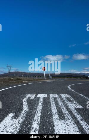 Grand lettrage « top » peint sur la route du tarmac et le panneau rouge vue du bas niveau avec le ciel bleu, les nuages et les montagnes enneigées en arrière-plan Banque D'Images