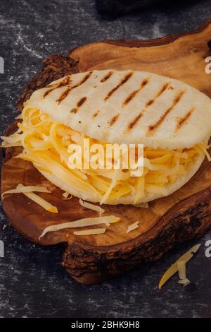 Arépa avec fromage jaune sur une planche en bois Banque D'Images