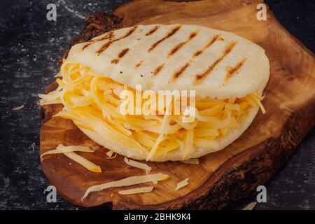 Arépa avec fromage jaune sur une planche en bois Banque D'Images